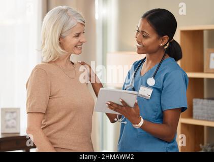 Stai andando a stare bene. Shot di un medico che usa un tablet digitale durante una consultazione con una donna anziana a casa. Foto Stock