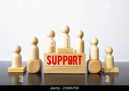 CONCETTO di PAROLA DI SUPPORTO scritto su blocchi di legno che giacciono su un tavolo chiaro con un fiore in un vaso di fiori su uno sfondo chiaro Foto Stock