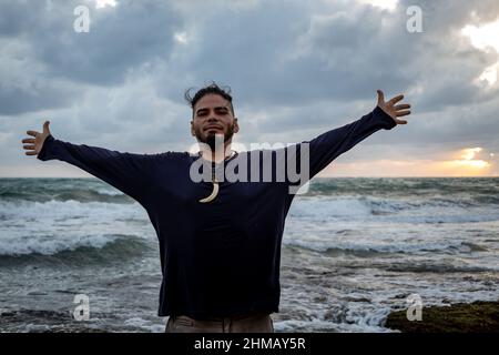 Uomo felice sulla spiaggia. Atteggiamento positivo di un giovane all'alba. Foto Stock