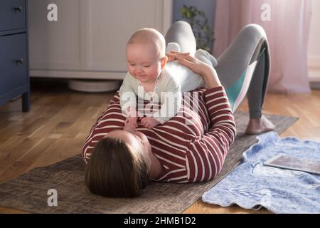 Madre con bambino fare yoga a casa per essere forte e sano Foto Stock