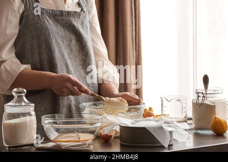 Donna che prepara gustosa cheesecake basca bruciata in cucina Foto Stock