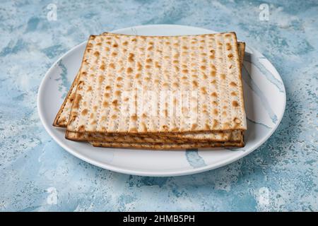 Piatto con pane piatto ebraico per la Pasqua su sfondo colorato Foto Stock