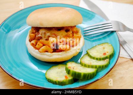 Panino con macaroni servito su una insalata di cetrioli con placcatura blu Foto Stock