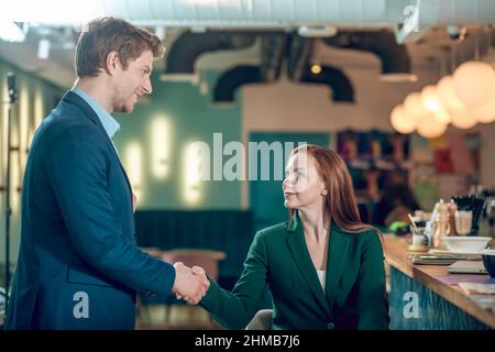 Uomo e donna che scuotono le mani in un caffè Foto Stock