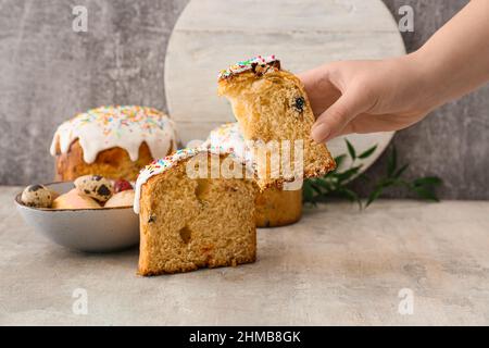 Donna che tiene un pezzo di dolce pasquale delizioso su sfondo grigio Foto Stock