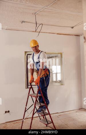 Allegro lavoratore maschio che fissa cavi elettrici in appartamento Foto Stock