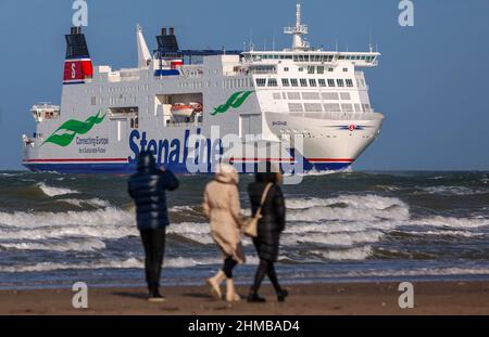 05 febbraio 2022, Meclemburgo-Pomerania occidentale, Warnemünde: Gli escursionisti guardano il traghetto StenaLine 'shane' entrare nel canale marittimo di Rostock dalla spiaggia. Foto: Jens Büttner/dpa-Zentralbild/ZB Foto Stock