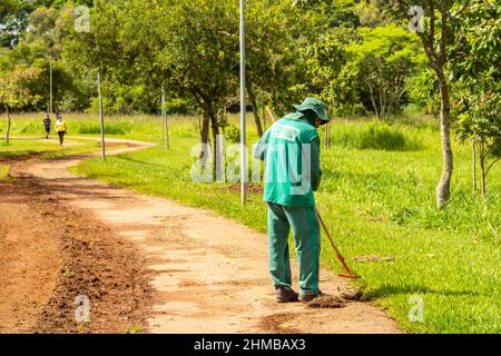 Goiânia, Goias, Brasile – 18 gennaio 2022: Un professionista del municipio che fa la manutenzione del prato in un parco pubblico. Foto Stock