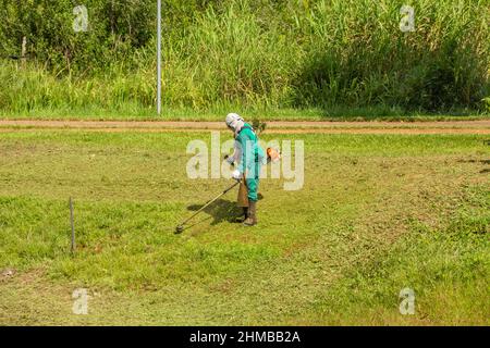 Goiânia, Goias, Brasile – 18 gennaio 2022: Un professionista del municipio che fa la manutenzione del prato in un parco pubblico. Foto Stock