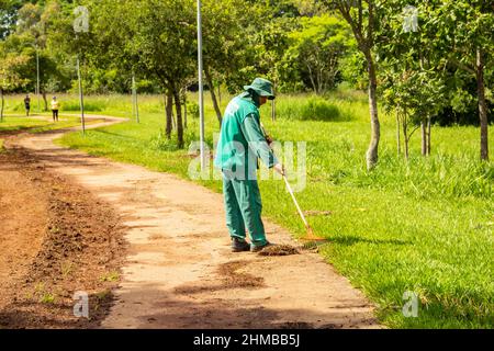 Goiânia, Goias, Brasile – 18 gennaio 2022: Un professionista del municipio che fa la manutenzione del prato in un parco pubblico. Foto Stock