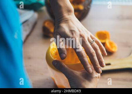 Primo piano ritratto delle mani della donna spremendo il succo di arancia matura in cucina. Cibo fresco e sano. Stile di vita sano. Nutrizione organica naturale. Foto Stock