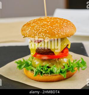 Grande hamburger doppio su piastra di pietra nera. Cheeseburger fatto in casa Foto Stock