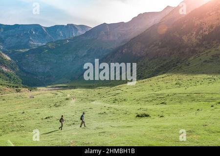 Giovane coppia escursioni in una bella valle tra le montagne durante il tramonto. Discovery Travel Destination Concept. Foto Stock
