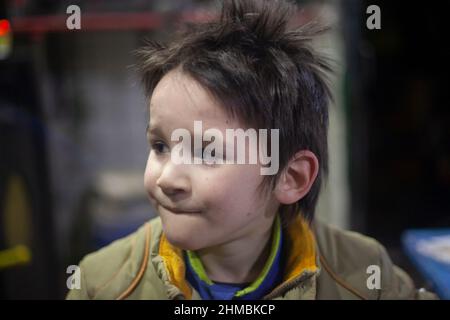 Ritratto di un ragazzo allegro e grimy. Primo piano di un bambino. Il volto di un ragazzo interessante. Emozioni nelle espressioni facciali di un bambino. Occhi Foto Stock