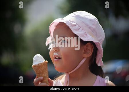 Un bambino mangia il gelato. La ragazza morde la dolcezza. Gelato estivo in mano al bambino. Un preschooler a Panama. Riposa in estate sulla strada. Foto Stock