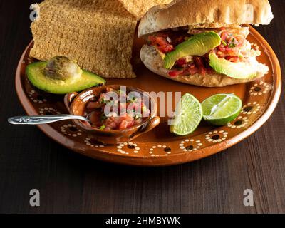 Bolillo ripieno di cicarron, avocado e salsa messicana (Guacamaya). Foto Stock