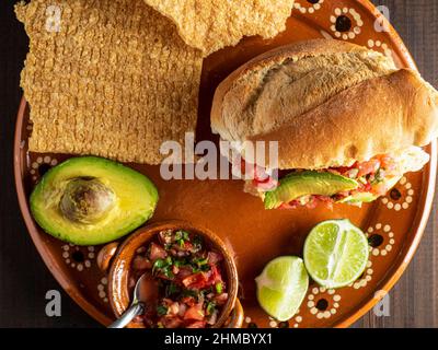 Bolillo ripieno di cicarron, avocado e salsa messicana (Guacamaya). Foto Stock