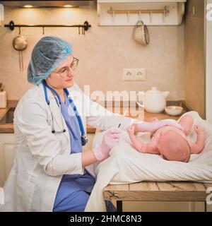 Il medico controlla la temperatura del neonato con un termometro. Un infermiere in uniforme misura la febbre del bambino con un termometro Foto Stock