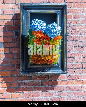 Retro piante di interior design in legno cornice sul muro di mattoni. Elegante arredamento di strada. Foto di strada, fuoco selettivo, nessuno. Foto Stock