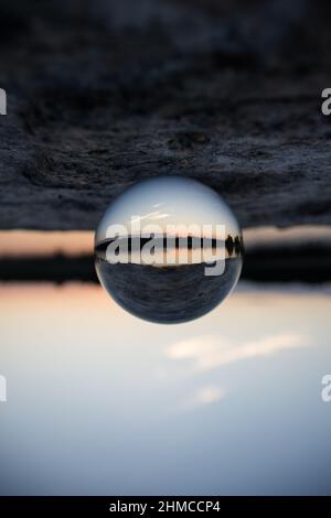 Foto di una palla di vetro di un tramonto su un lago Foto Stock