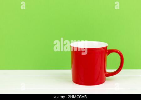 Primo piano di una tazza rossa su sfondo verde con spazio per la copia Foto Stock