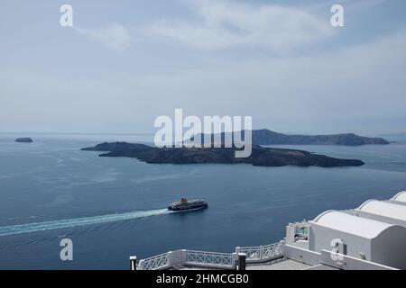 Santorini, Grecia - 7 maggio 2021 : un traghetto che parte dal porto di Santorini e passa accanto al famoso vulcano Nea Kameni Foto Stock