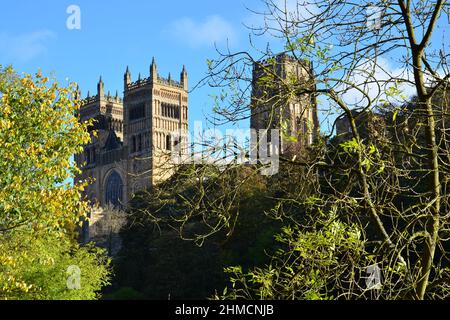 Primo piano delle maestose torri della cattedrale di Durham contro un profondo cielo blu e alberi dorati all'esterno in una giornata di sole Foto Stock