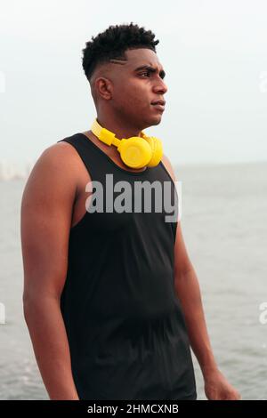 Uomo in abbigliamento sportivo con cuffie sulla strada per la palestra Foto Stock