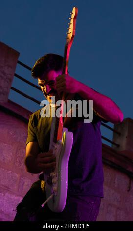 il giovane chitarrista si esibisce con passione su un palco durante un concerto serale Foto Stock