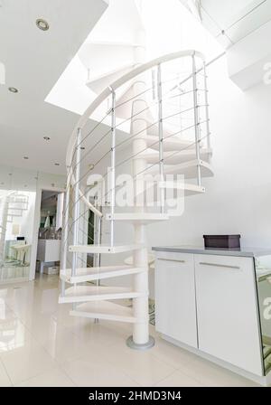 una scala a chiocciola bianca che conduce ad una terrazza al piano superiore all'interno di una casa a tema bianco Foto Stock