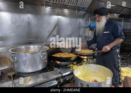 Un volontario in un tempio Sikh cuoca cibo vegetariano che sarà alimentato a chiunque chiede. A South Richmond Hill, Queens, New York City. Foto Stock