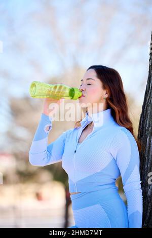 bella giovane donna europea in abbigliamento sportivo acqua potabile dopo l'allenamento Foto Stock