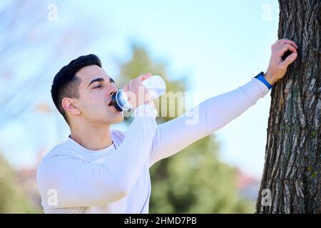 bel giovane europeo in abbigliamento sportivo acqua potabile dopo l'allenamento Foto Stock