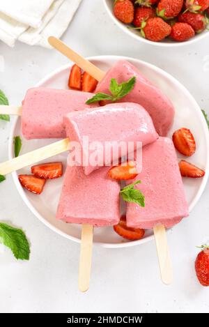 Popsicle di gelato alla fragola su piatto bianco Foto Stock