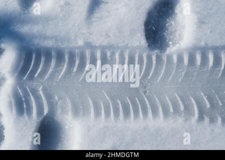 Pista per pneumatici e alcune impronte sulla neve nella stagione invernale. Foto Stock