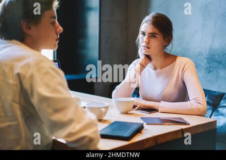 Donna che guarda l'uomo mentre si siede in un bar Foto Stock