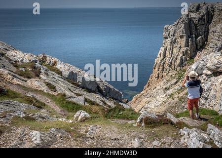 Vista posteriore dell'uomo ammirando il mare dalla scogliera rocciosa, Bretagna, Francia Foto Stock