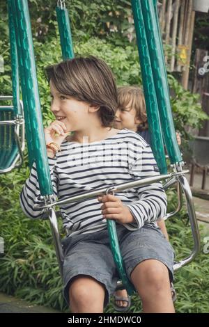 Sorridendo i ragazzi che si divertono mentre cavalcate sul trambing al parco divertimenti Foto Stock