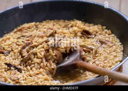 Cottura Risotto ai funghi con cucchiaio di legno. Foto di alta qualità. Foto Stock