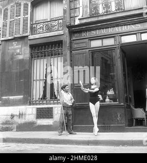 Ballerina nel 1950s. Ellen Rasch, 1920-2015, balletdancer svedese e foto di attrice a Parigi Francia in piedi sulle sue dita tenendo un antico fuori di un negozio, mentre un pulitore di strada guarda sopra, in pausa nel suo lavoro. 1951 Foto Kristoffersson Ref BD26-5 Foto Stock