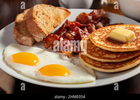 colazione all'americana completa tradizionale con uova, pancake con pancetta e pane tostato Foto Stock