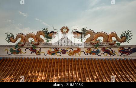 La scultura dei draghi cinesi gemellati decorano sul tetto del tempio in stile cinese su sfondo cielo blu. Messa a fuoco selettiva. Foto Stock