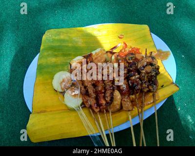 Sate e lontong (torta di riso, rotolo di riso) sul piatto e lasciare la banana. Il Sate è uno dei piatti tradizionali indonesiani serviti con salsa di arachidi Foto Stock