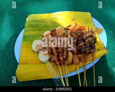 Sate e lontong (torta di riso, rotolo di riso) sul piatto e lasciare la banana. Il Sate è uno dei piatti tradizionali indonesiani serviti con salsa di arachidi Foto Stock