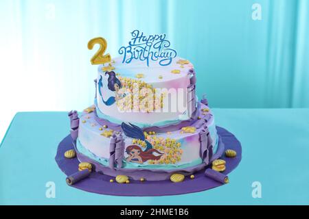 Torta di compleanno a tema princess a due livelli splendidamente disegnata e decorata con burro viola e rosa e una ciliegina fondente con corona di perle Foto Stock