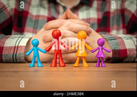 Concetto di assicurazione di famiglia con figurine di famiglia colorate su tavola di legno Foto Stock