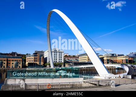 Vista del Gateshead Millennium Bridge a Newcastle upon Tyne e Gateshead (Inghilterra), con Newcastle banchina, in una giornata di sole Foto Stock