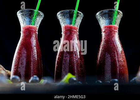 Frullati con barbabietole, mirtilli e menta in vaso di vetro con frutta e verdura sul tavolo di legno. Disintossicazione, dieta, sano, cibo vegetariano conce Foto Stock