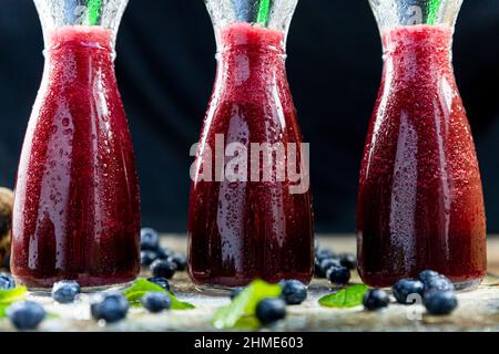 Spremuta con barbabietola, mirtilli e menta in vaso di vetro con frutta e verdura sul tavolo di legno. Disintossicazione, dieta, sano, vegetariano concetto di cibo Foto Stock