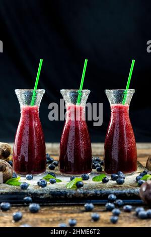 Spremuta con barbabietola, mirtilli e menta in vaso di vetro con frutta e verdura sul tavolo di legno. Disintossicazione, dieta, sano, vegetariano concetto di cibo Foto Stock